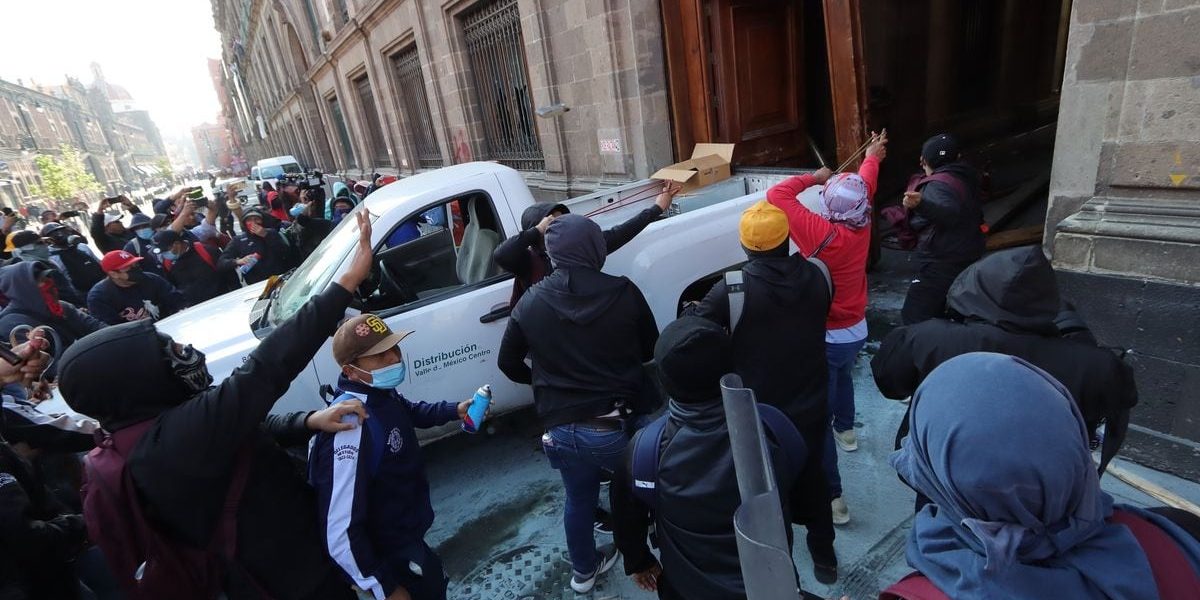 Grupo de normalistas derriban la puerta del Palacio Nacional
